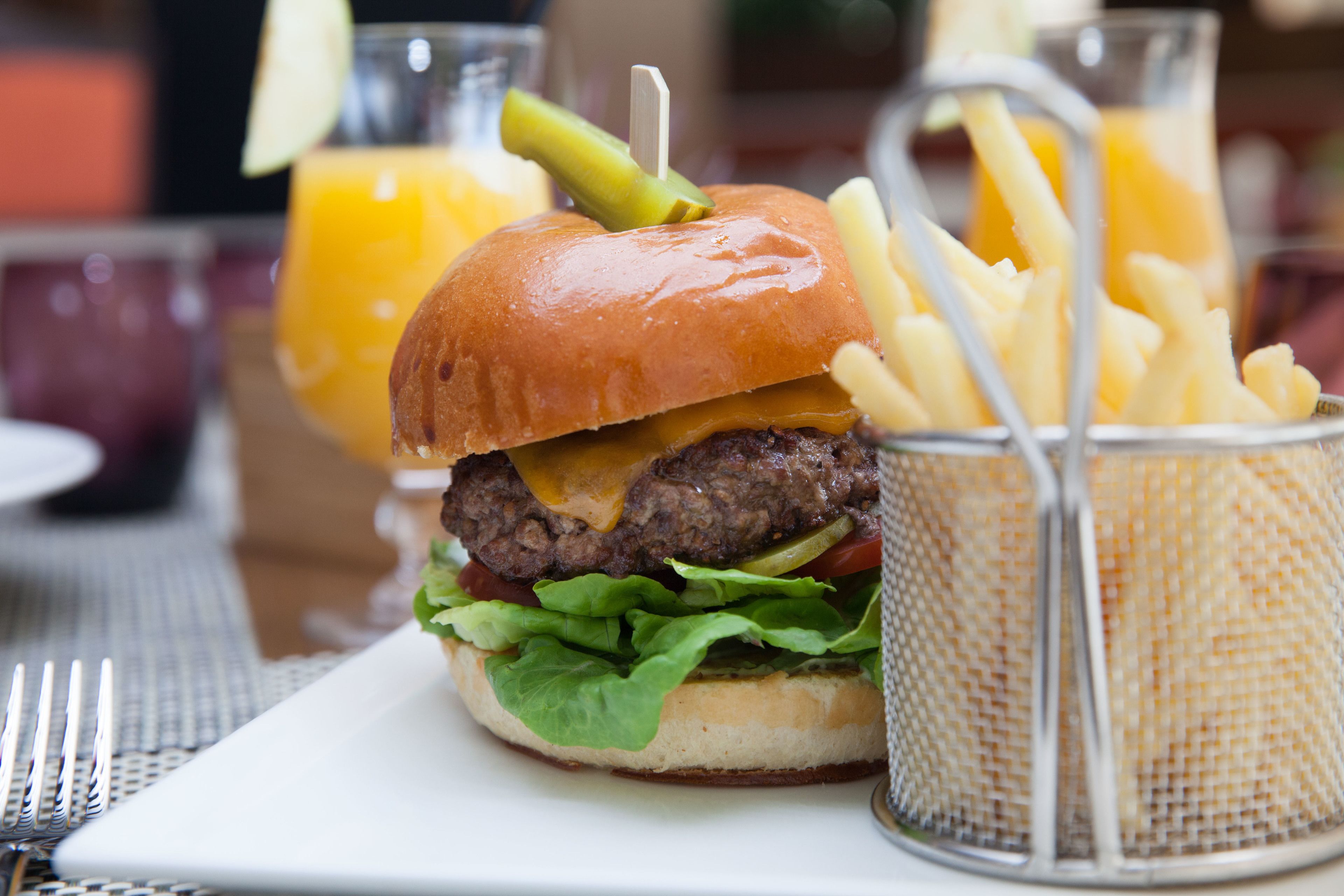 A burger with fries and a drink on a table.