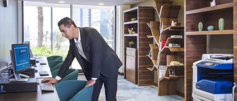 Una oficina moderna con un escritorio, computadora e impresora. Se observa una estantería con libros y objetos decorativos.