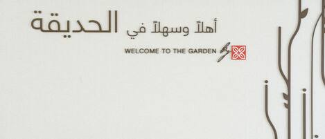A welcome sign with Arabic text and a logo.