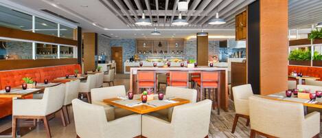 A modern restaurant with a brick wall, wooden accents, and a central bar area.