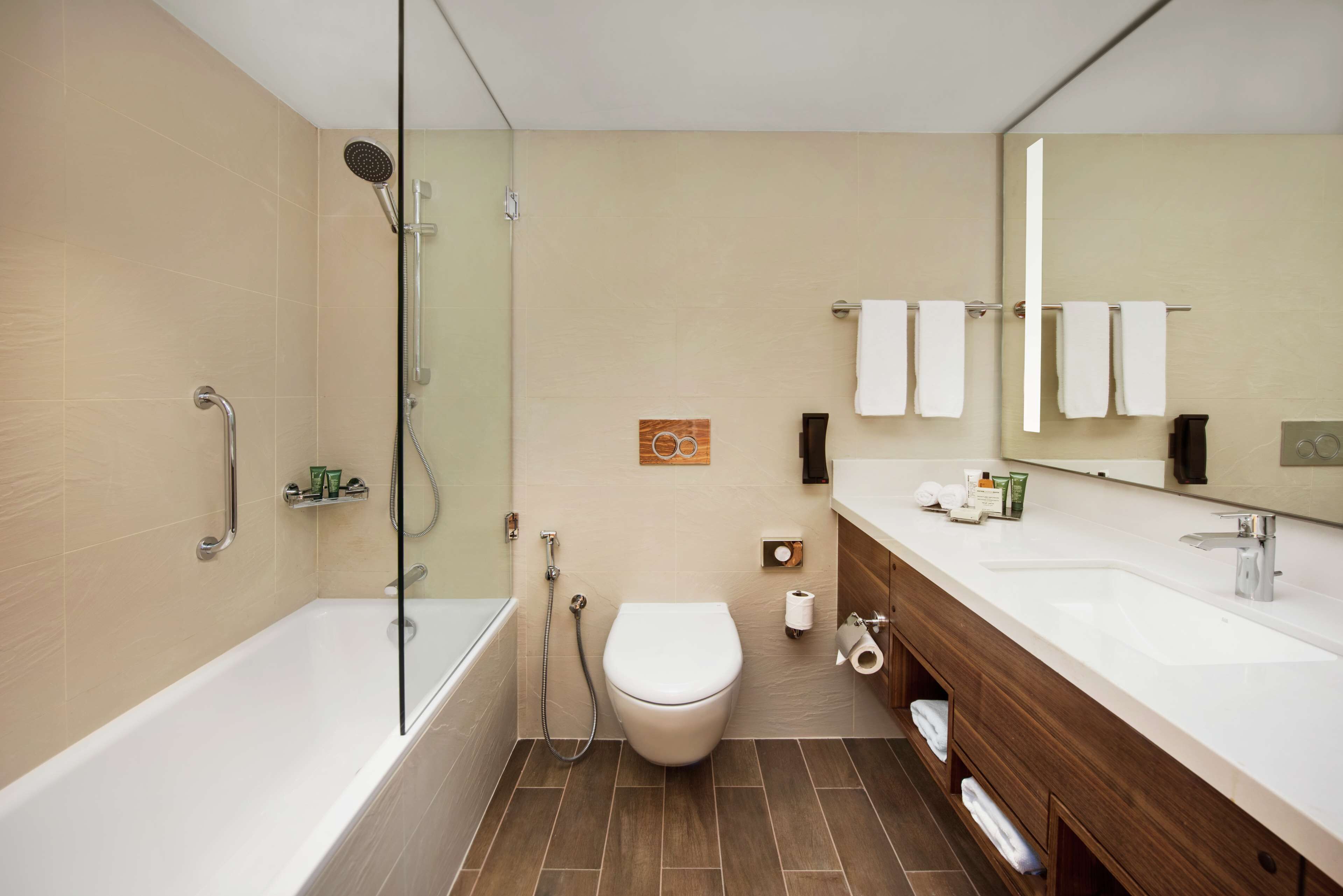 A modern bathroom with a bathtub, toilet, and a large mirror.