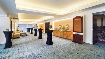 A hotel lobby with a reception desk, seating area, and a large carpeted space.
