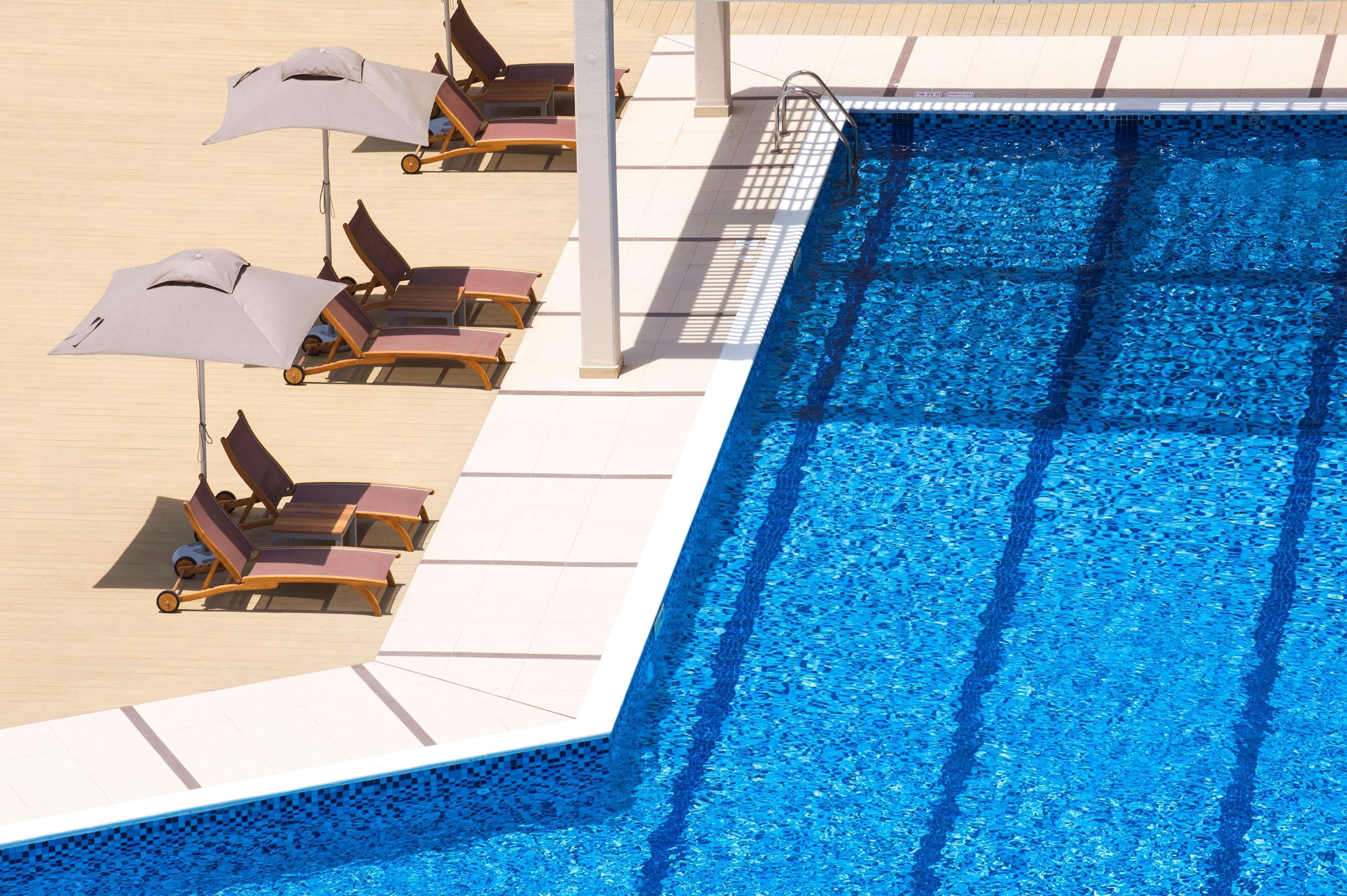 A poolside area with sun loungers and umbrellas.