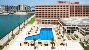 A hotel with a large pool, outdoor seating, and a view of the sea.