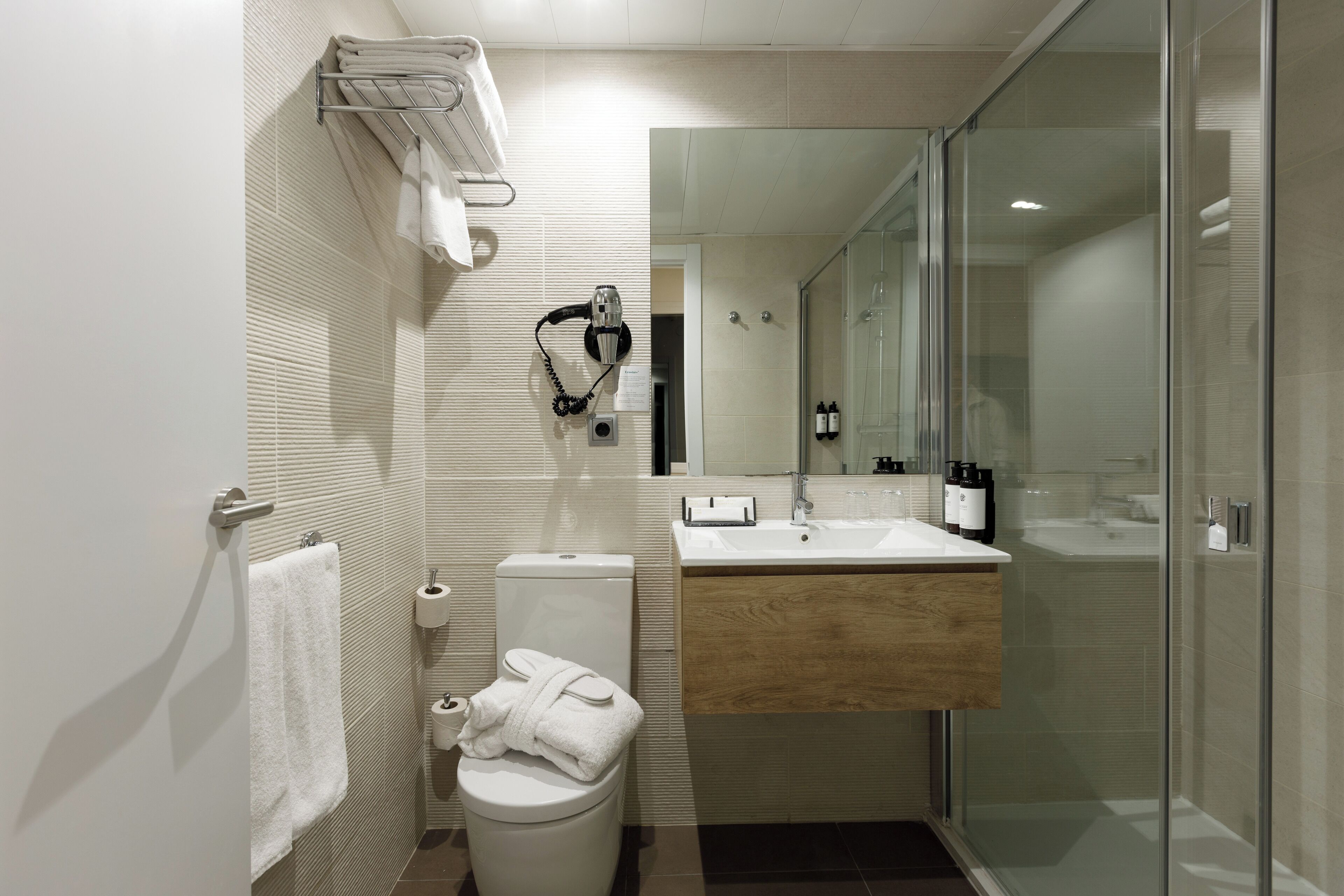 A modern bathroom with a toilet, sink, and glass shower enclosure.