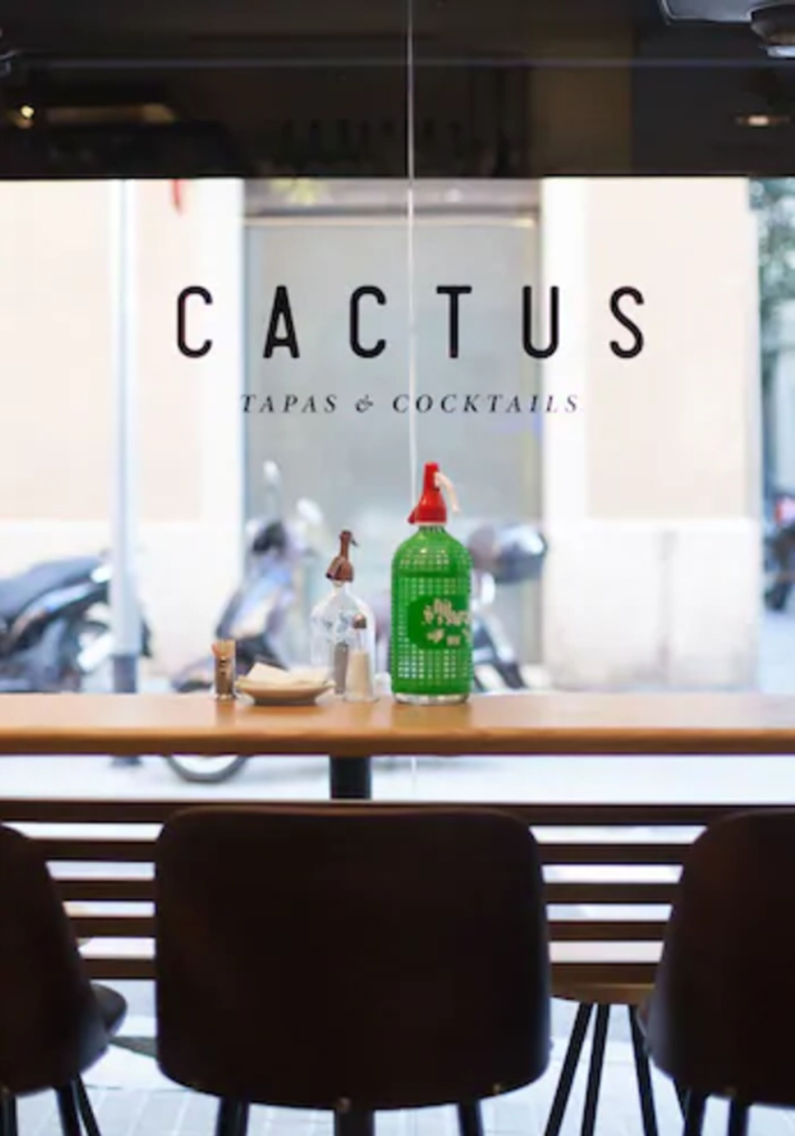 A restaurant named 'Cactus Tapas & Cocktails' with a wooden table and chairs in front of a window.