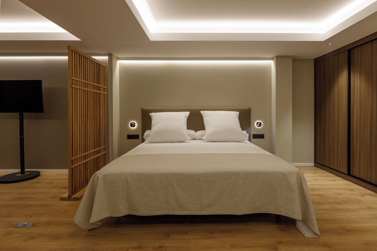 Une chambre moderne avec un grand lit, un plancher en bois et une armoire intégrée.