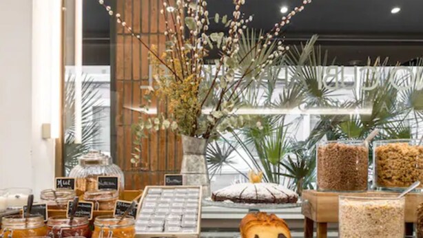 Een bakkerijdisplay met potten jam, gebak en een decoratieve bloemenarrangement.