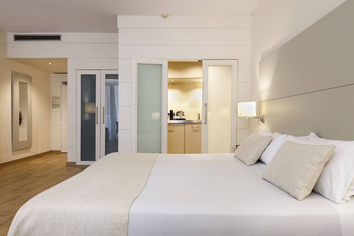 Une chambre d’hôtel moderne dotée d’un grand lit, d’un dressing et d’une kitchenette.