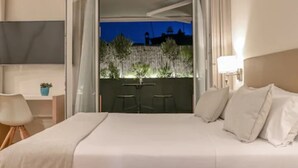 Een hotelkamer met een bed, een bureau, een stoel en uitzicht op buiten.