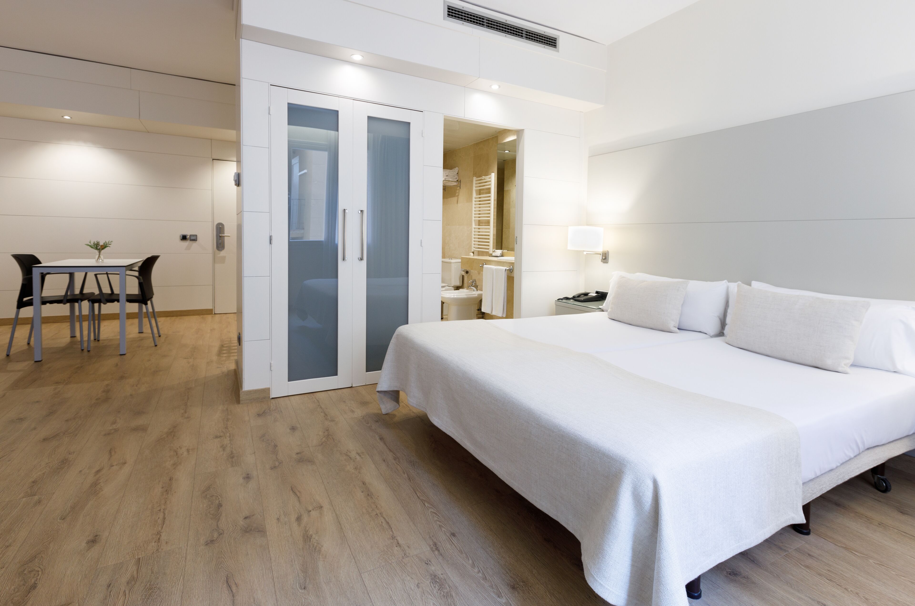 Habitación de hotel con una cama grande, un escritorio con una silla y un baño independiente.