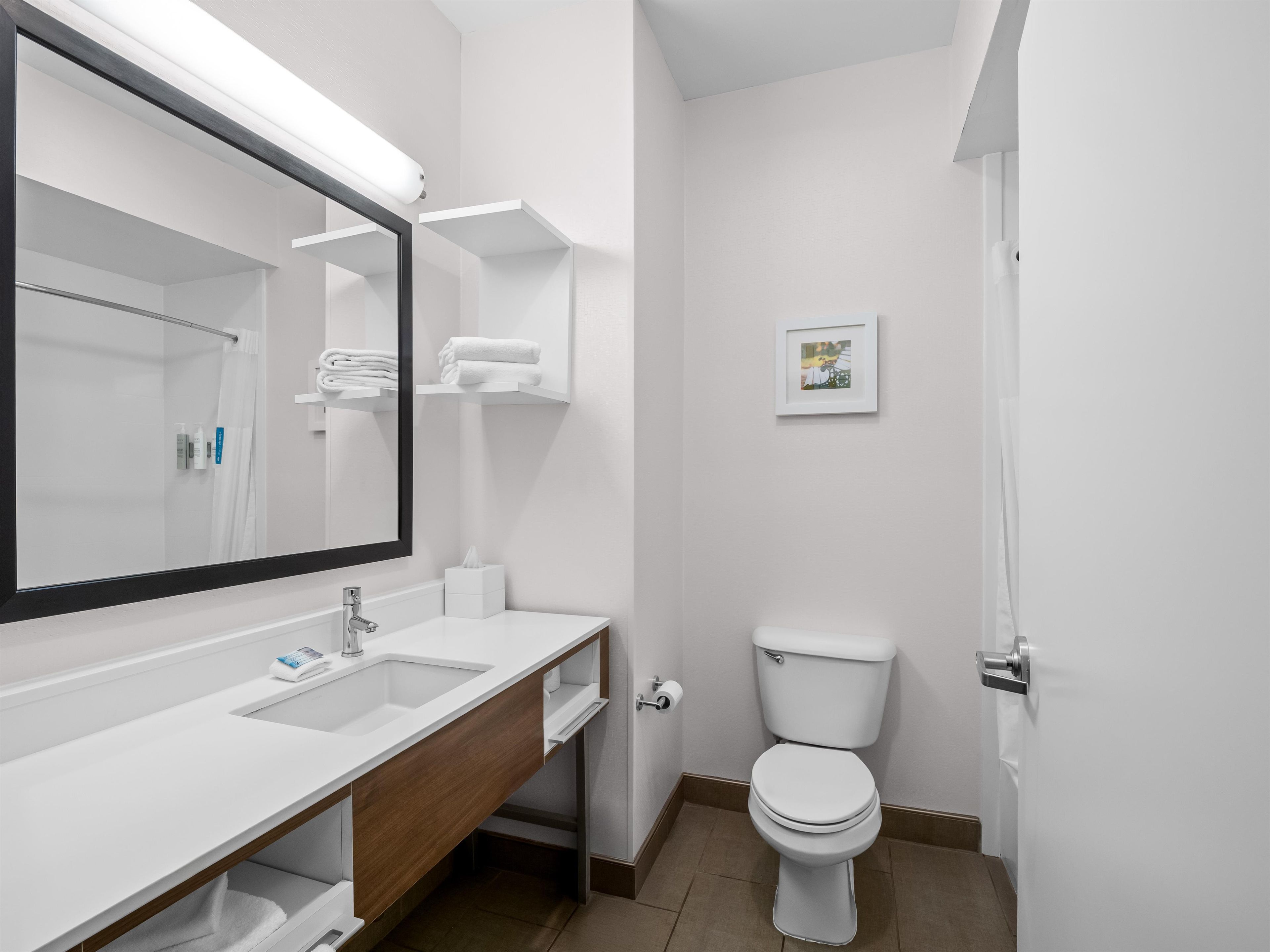 A modern bathroom with a large mirror, white sink, and toilet.