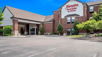 A Hampton Inn & Suites by Hilton with a brick facade, a covered entrance, and a parking lot.
