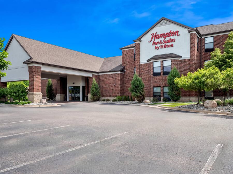 A Hampton Inn & Suites by Hilton with a brick facade, a covered entrance, and a parking lot.