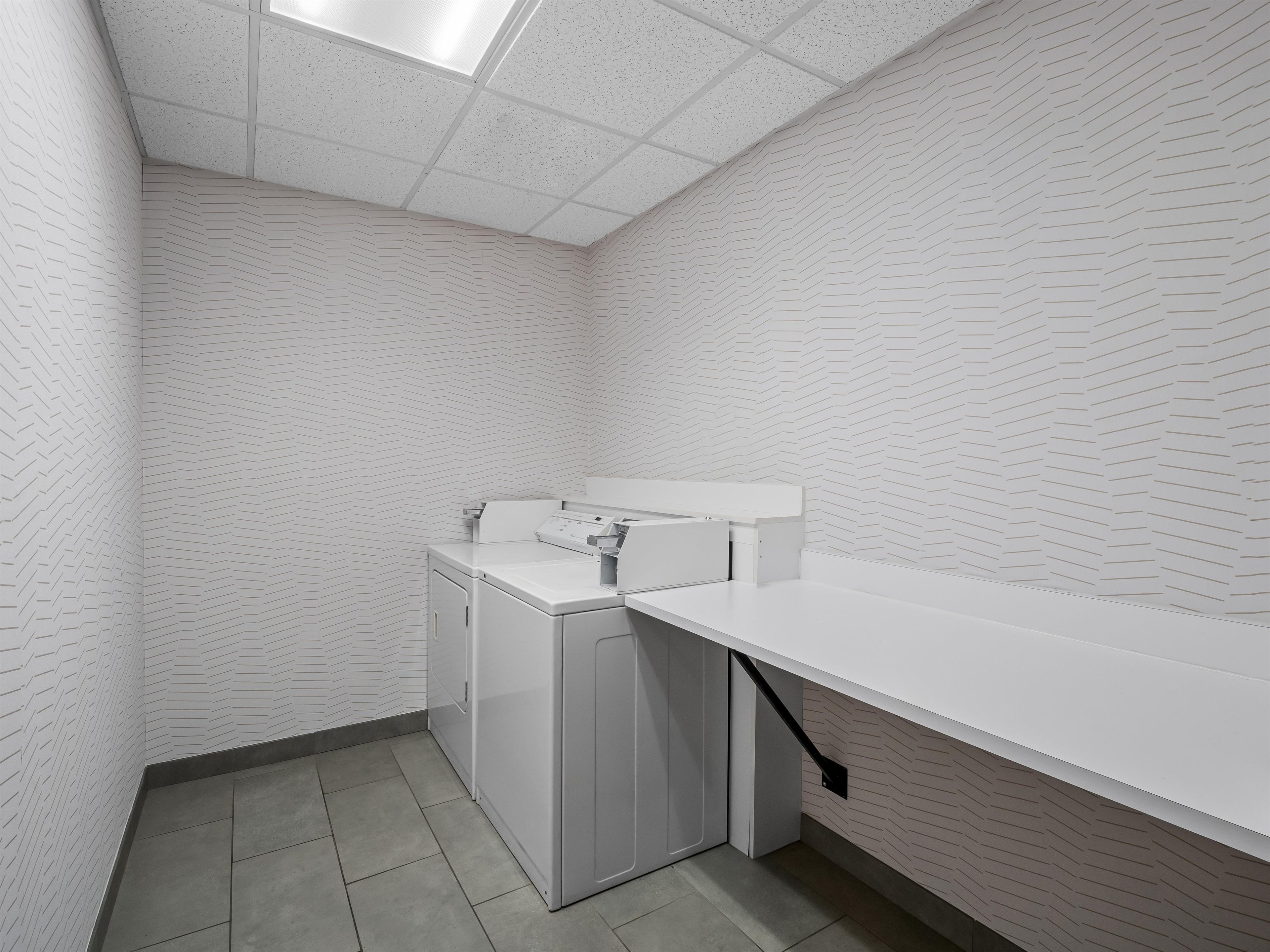 A laundry room with a washing machine, a dryer, and a countertop.