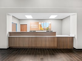 Una recepción con un letrero que dice 'Welcome to Hampton', una barra de madera y vistas a la ciudad.