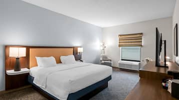 A hotel room with a large bed, bedside tables, a desk, and a chair.