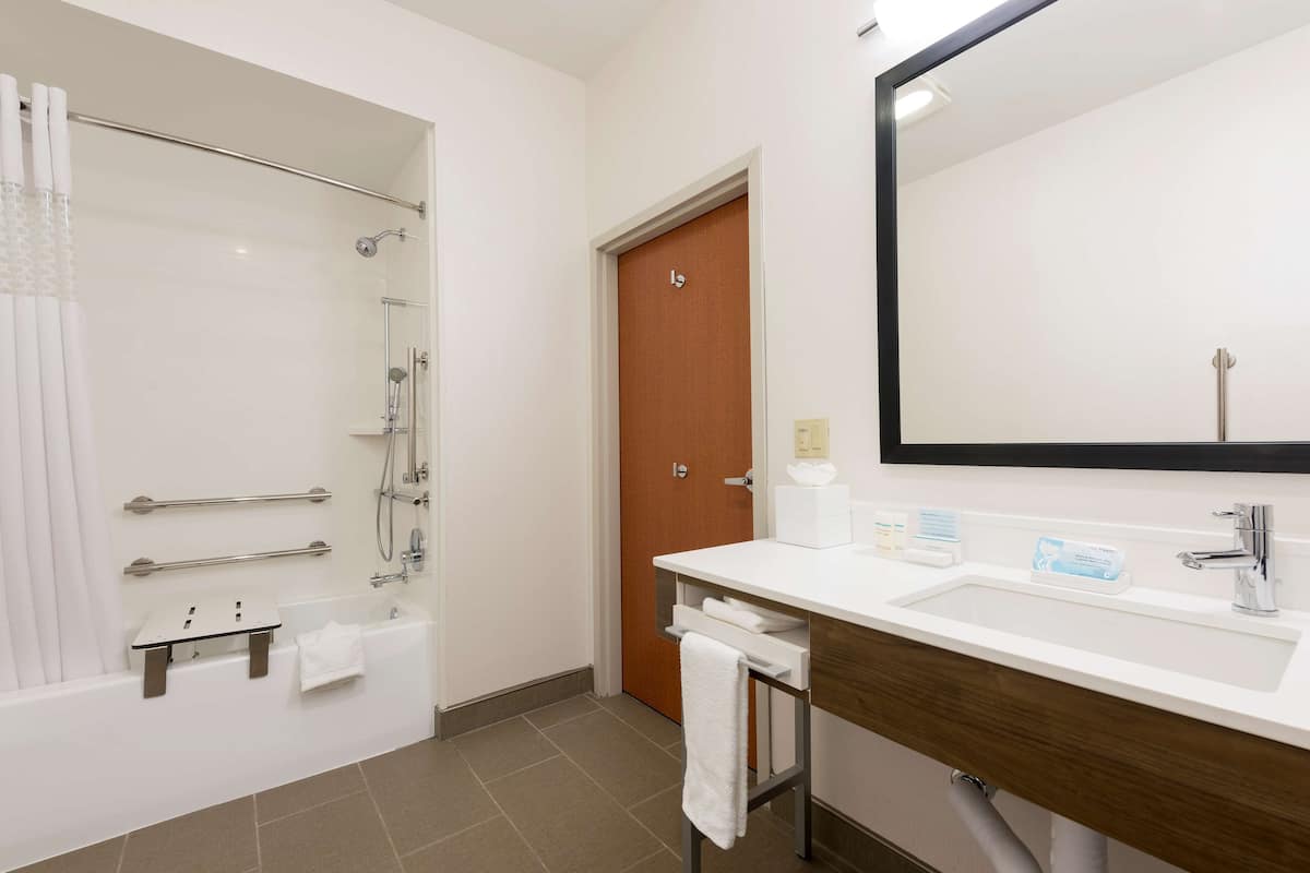 A modern bathroom with a shower, a sink, and a mirror.