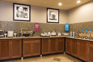 Una cocina de hotel con una estación de café, un expositor de alimentos y un dispensador de bebidas.