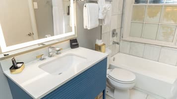 Une salle de bain moderne avec un lavabo blanc, un meuble-lavabo bleu, des toilettes et une baignoire.