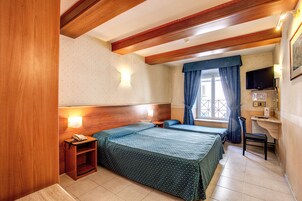 Una camera d'albergo con due letti, una scrivania, una sedia, una televisione e un telefono.