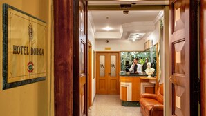 A hotel lobby with a bar area, a reception desk, and a leather sofa. - Hotel Dorica (Rome)