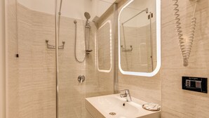 Uma casa de banho moderna com cabine de duche em vidro, toucador com lavatório e espelho.