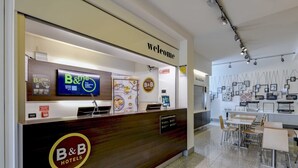 A B&B hotel reception desk with a digital screen, a 'Welcome' sign, and a menu board. - B&B Hotel Verona (Verona)