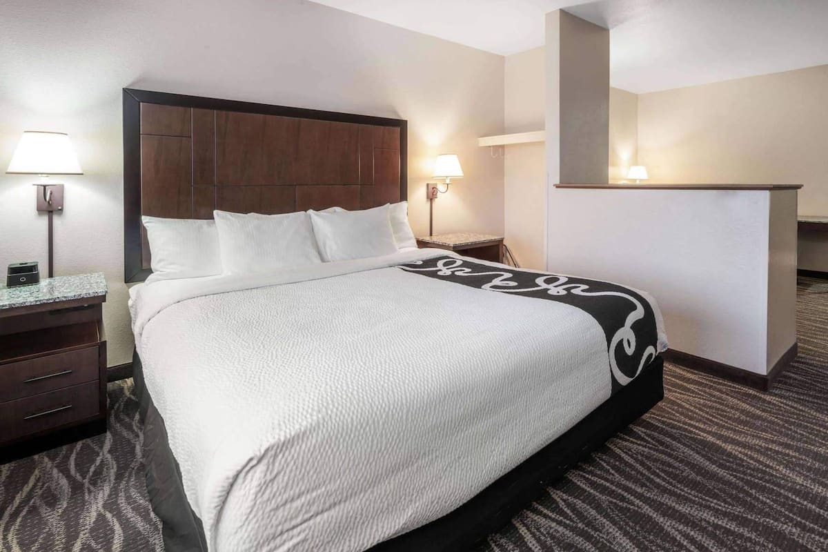 Una habitación de hotel con una cama, un escritorio, una silla y una mesita.