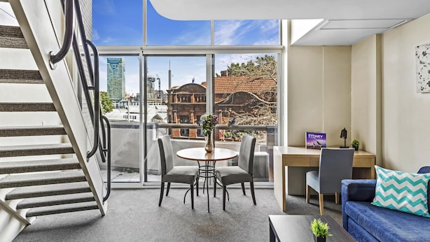 Ein modernes Wohnzimmer mit Treppe, Essbereich und Blick auf die Skyline von Sydney.