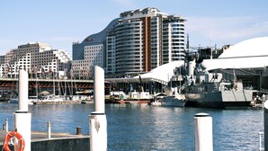 Ein Yachthafen mit einem großen Schiff, einer Brücke und modernen Gebäuden im Hintergrund.