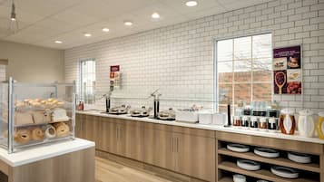 Un bar à petit-déjeuner proposant une variété de viennoiseries et de boissons, des meubles en bois et un mur en briques en arrière-plan.