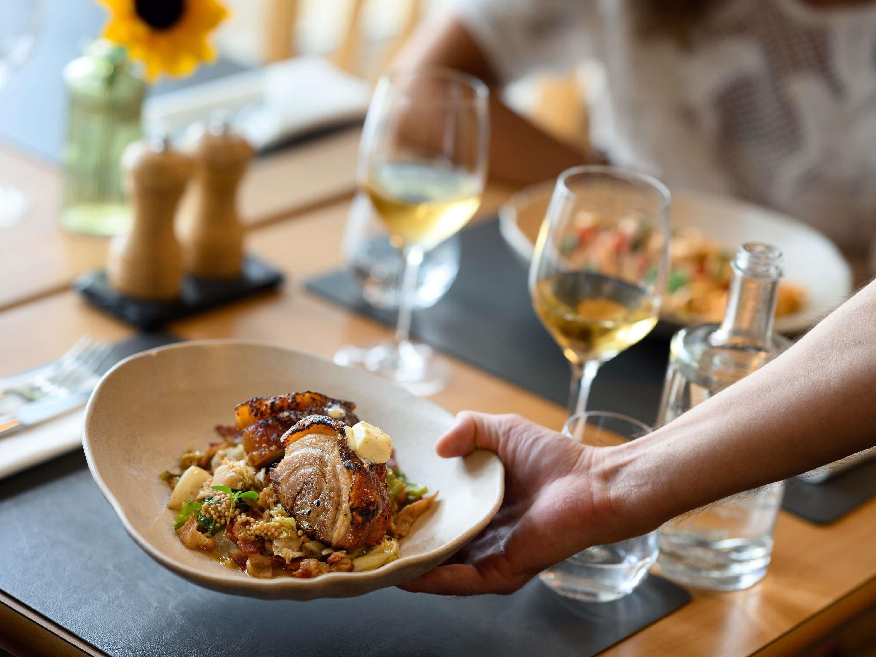 Une table à manger avec une assiette de nourriture, un verre à vin et une bouteille.
