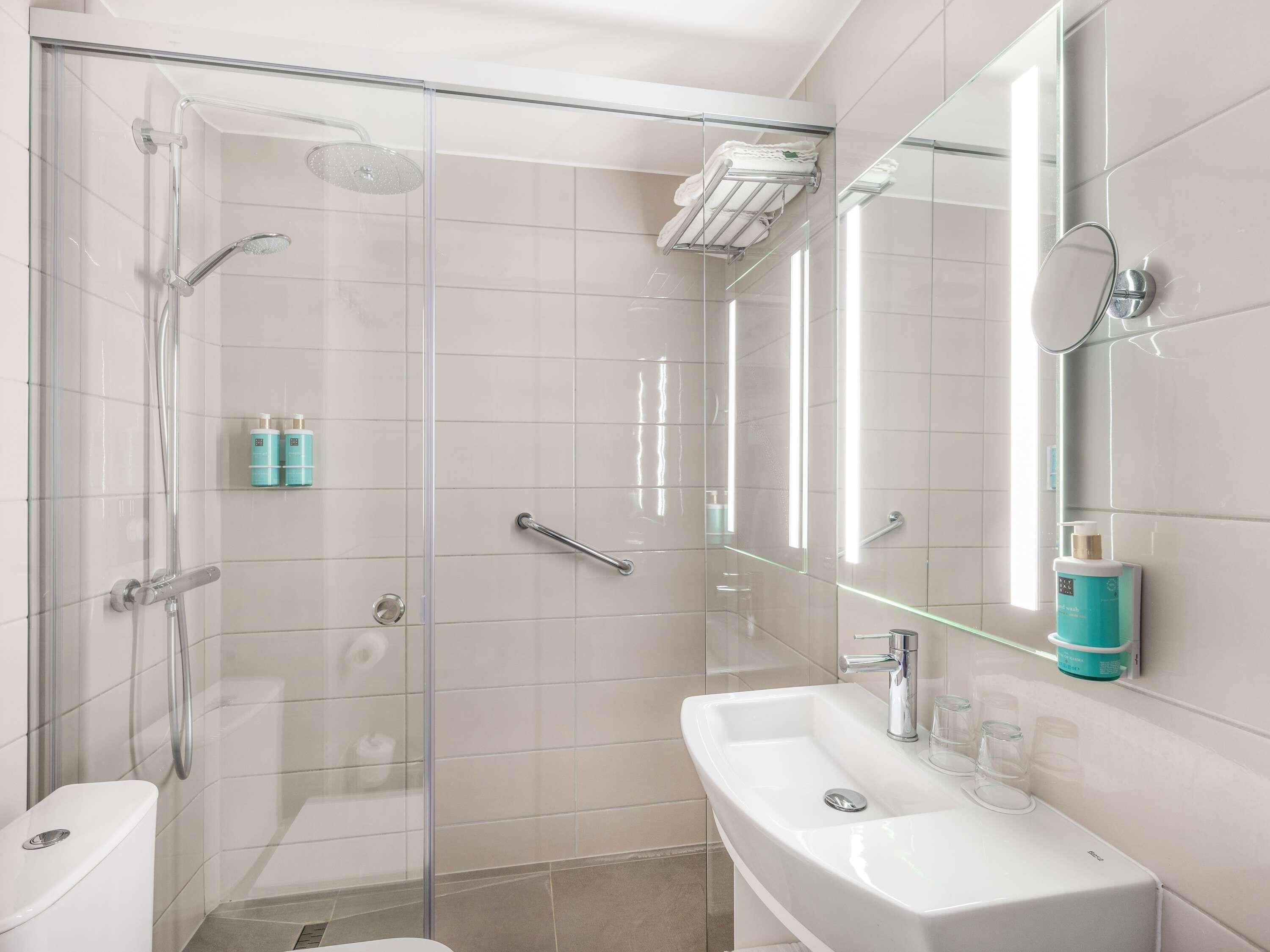 A modern bathroom with a glass shower enclosure, a white sink, and a mirror.