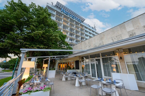 A hotel with outdoor seating, a covered patio, and a view of the hotel building in the background.