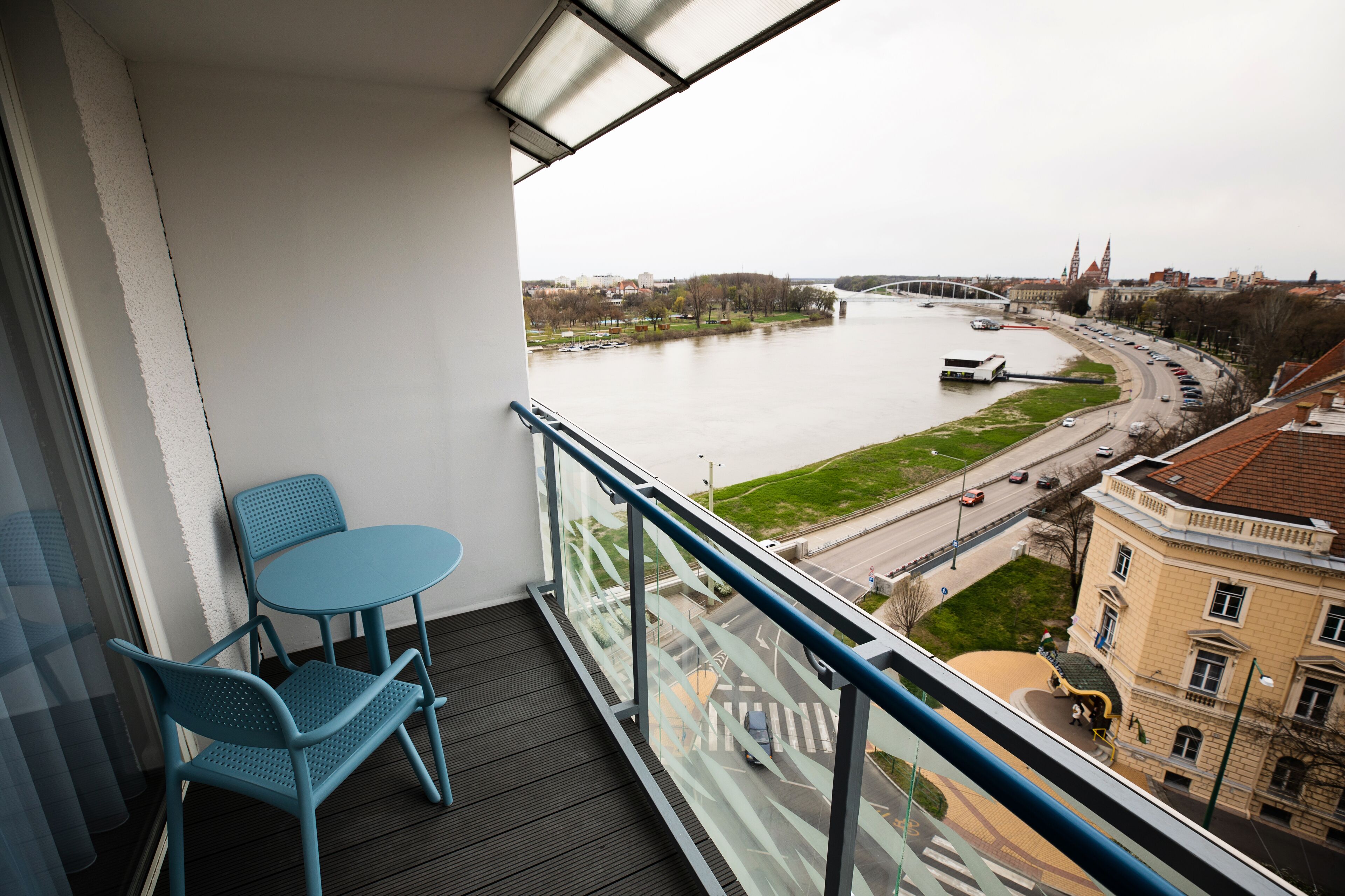 Un balcon avec vue sur une rivière, un pont et le paysage urbain.