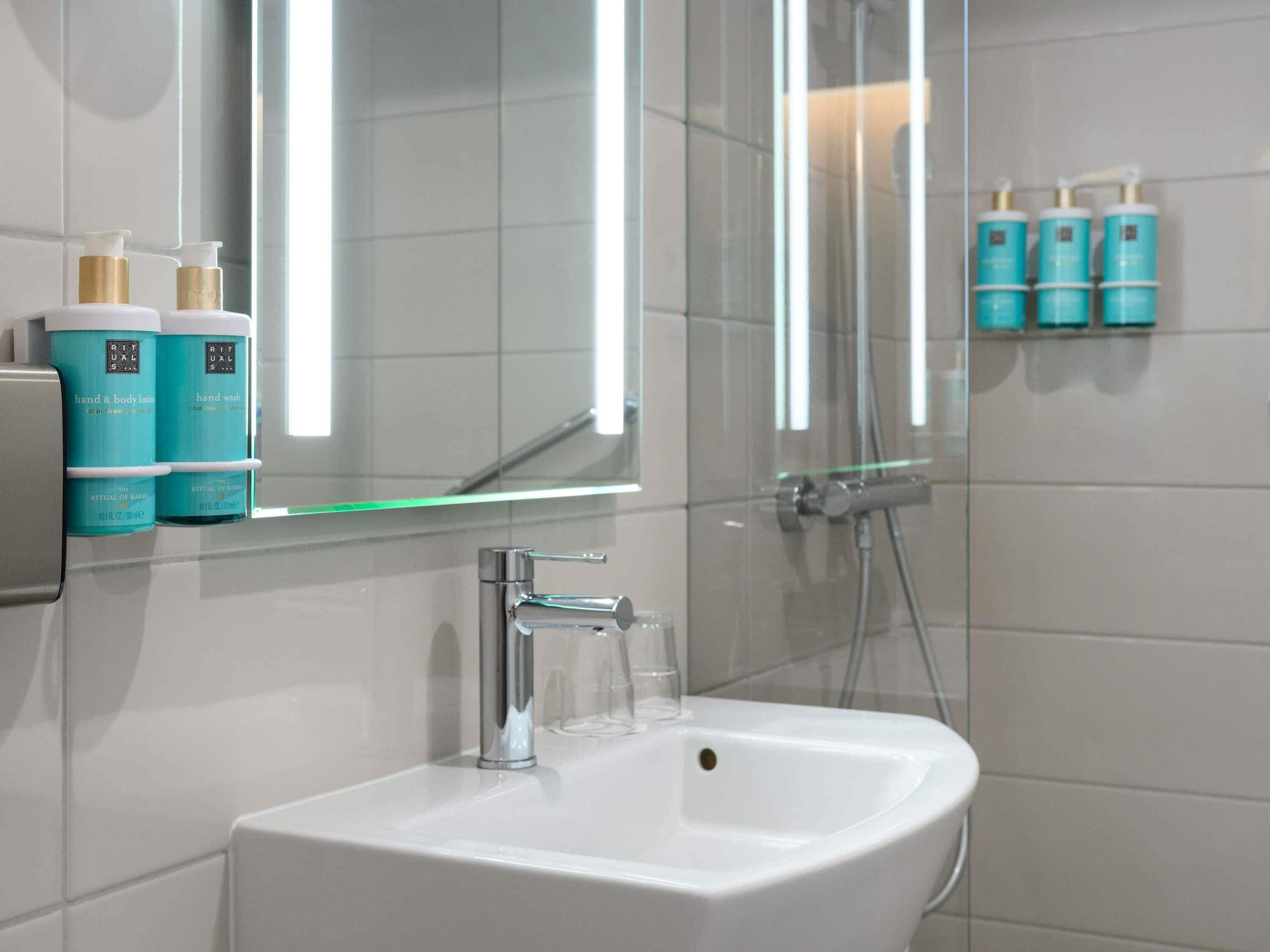 A bathroom with a white sink, a mirror, and a glass shower enclosure.