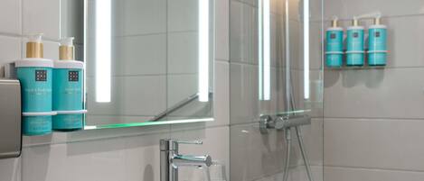 A bathroom with a white sink, a mirror, and a glass shower enclosure.