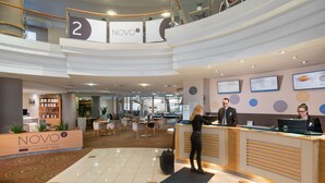 A modern hotel lobby with a reception desk, lounge bar, and seating area. - Novotel Szeged (Szeged)