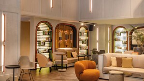 Eine geräumige Lobby mit hohen Decken, gewölbten Durchgängen und verschiedenen Sitzgelegenheiten, darunter Sofas und Sessel.