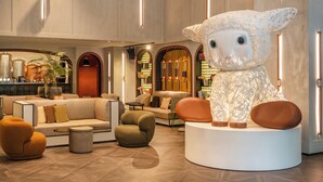 Eine moderne Lobby mit einer großen, weißen Skulptur, bequemen Sitzgelegenheiten und einer Bar.