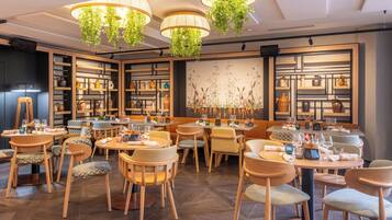 A restaurant with wooden furniture, hanging plants, and shelves with kitchenware.