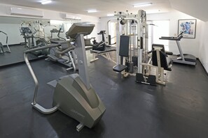 A gym with various exercise equipment, including treadmills, weight machines, and a stationary bike.
