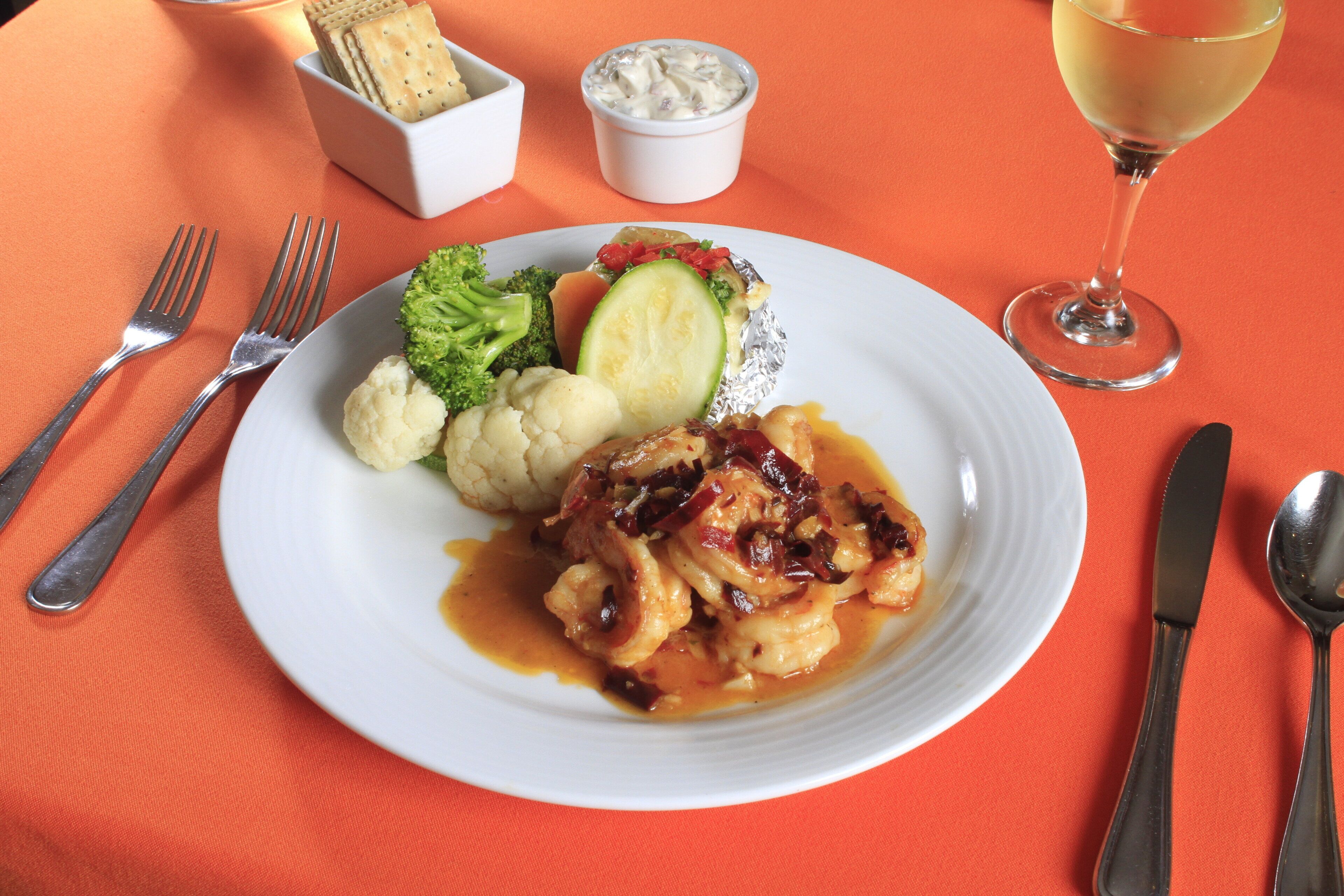 Une assiette de nourriture accompagnée d’un verre de vin, le tout posé sur une nappe orange.