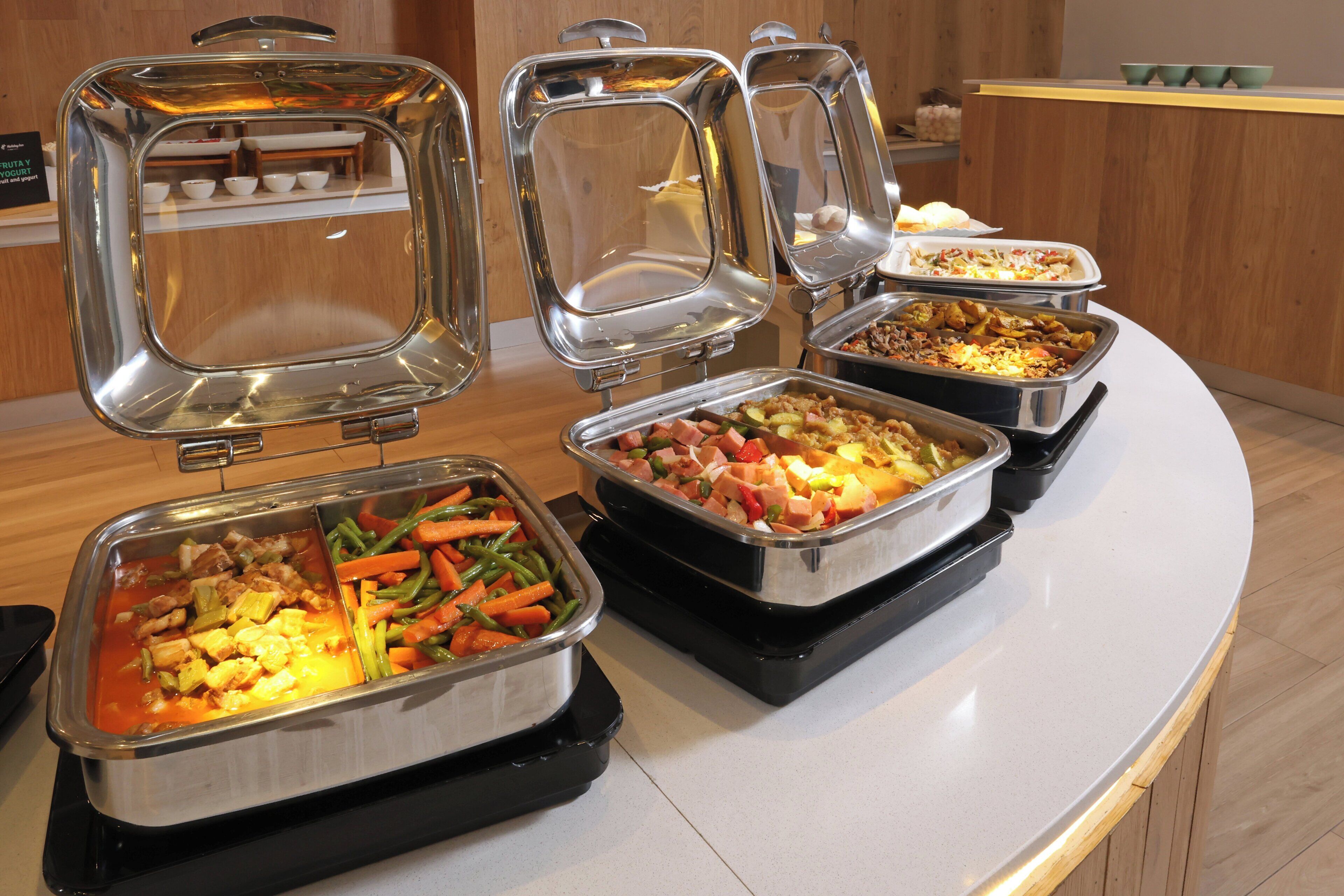 A buffet with various food items in metal serving trays.