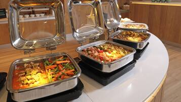 A buffet with various food items in metal serving trays.