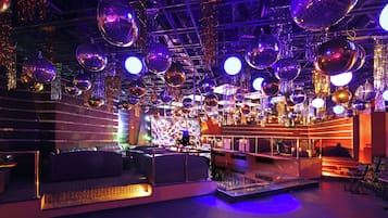 Una sala con múltiples bolas de discoteca, zonas de estar y un escenario.