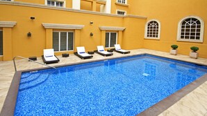 Una piscina con cuatro tumbonas y dos macetas.