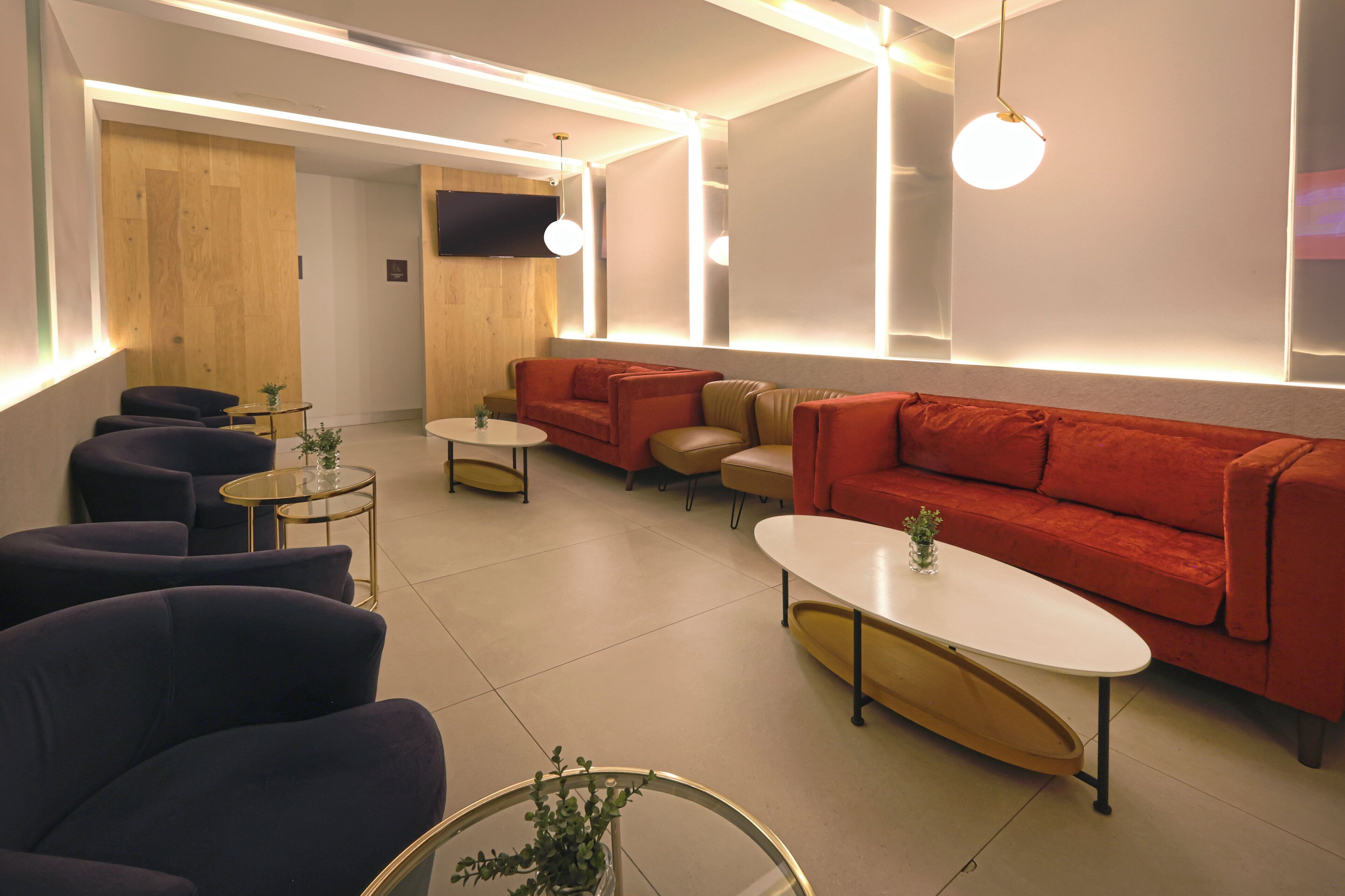Ein stilvoller Lounge-Bereich mit Sofas, Sesseln und runden Tischen, der ein minimalistisches Design und eine gedämpfte Beleuchtung aufweist.