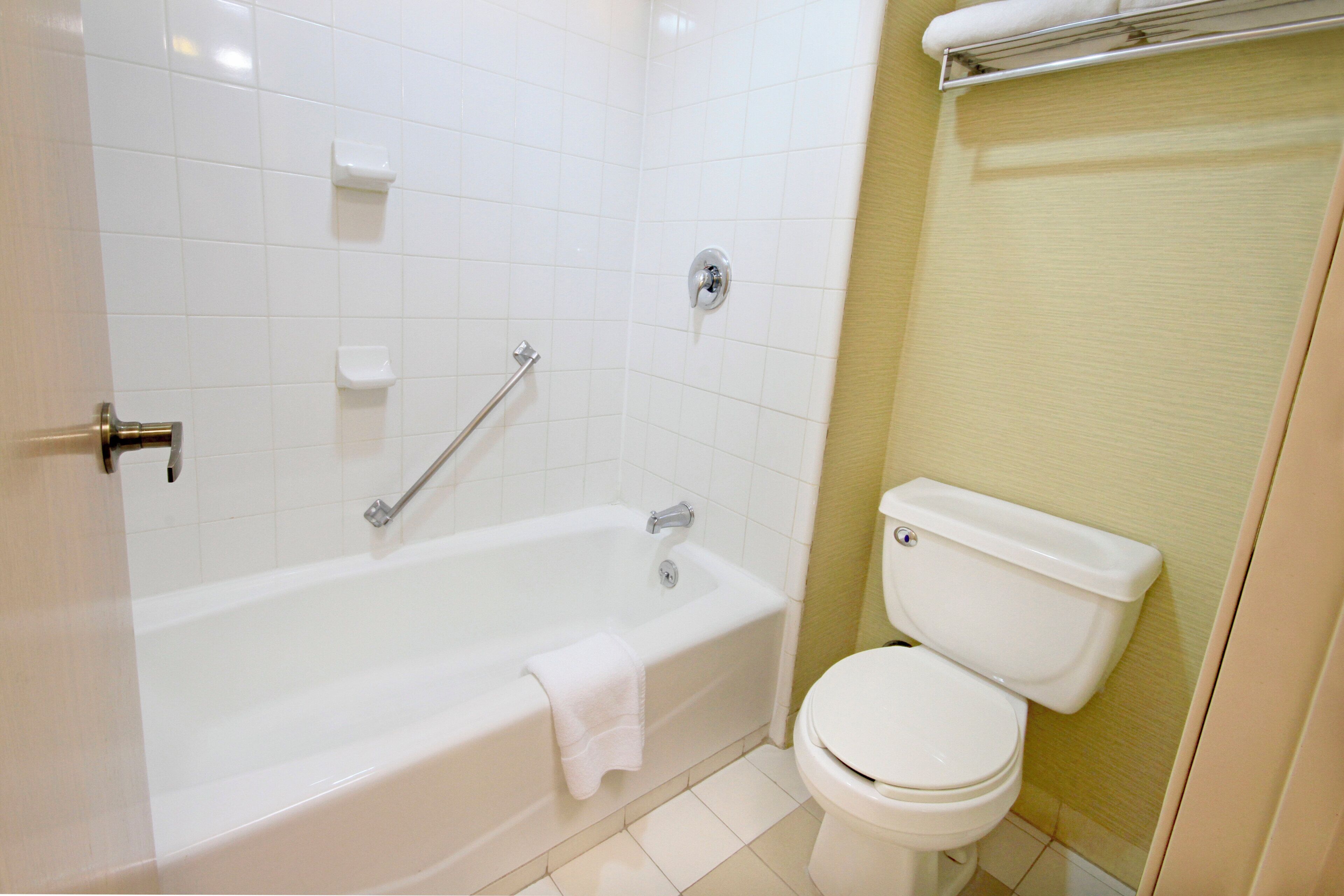 A bathroom with a bathtub, toilet, and a towel rack.